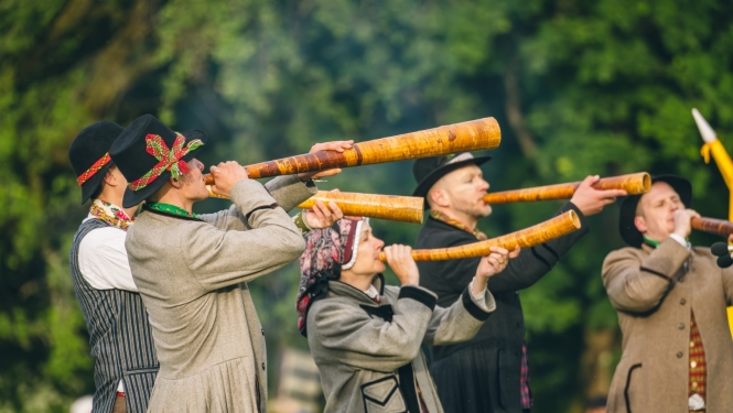 Folkloras festivāla Baltica dalībnieki ir ģērbušies tradicionālā tautastērpā spēlē koka pūšaminstrumentus