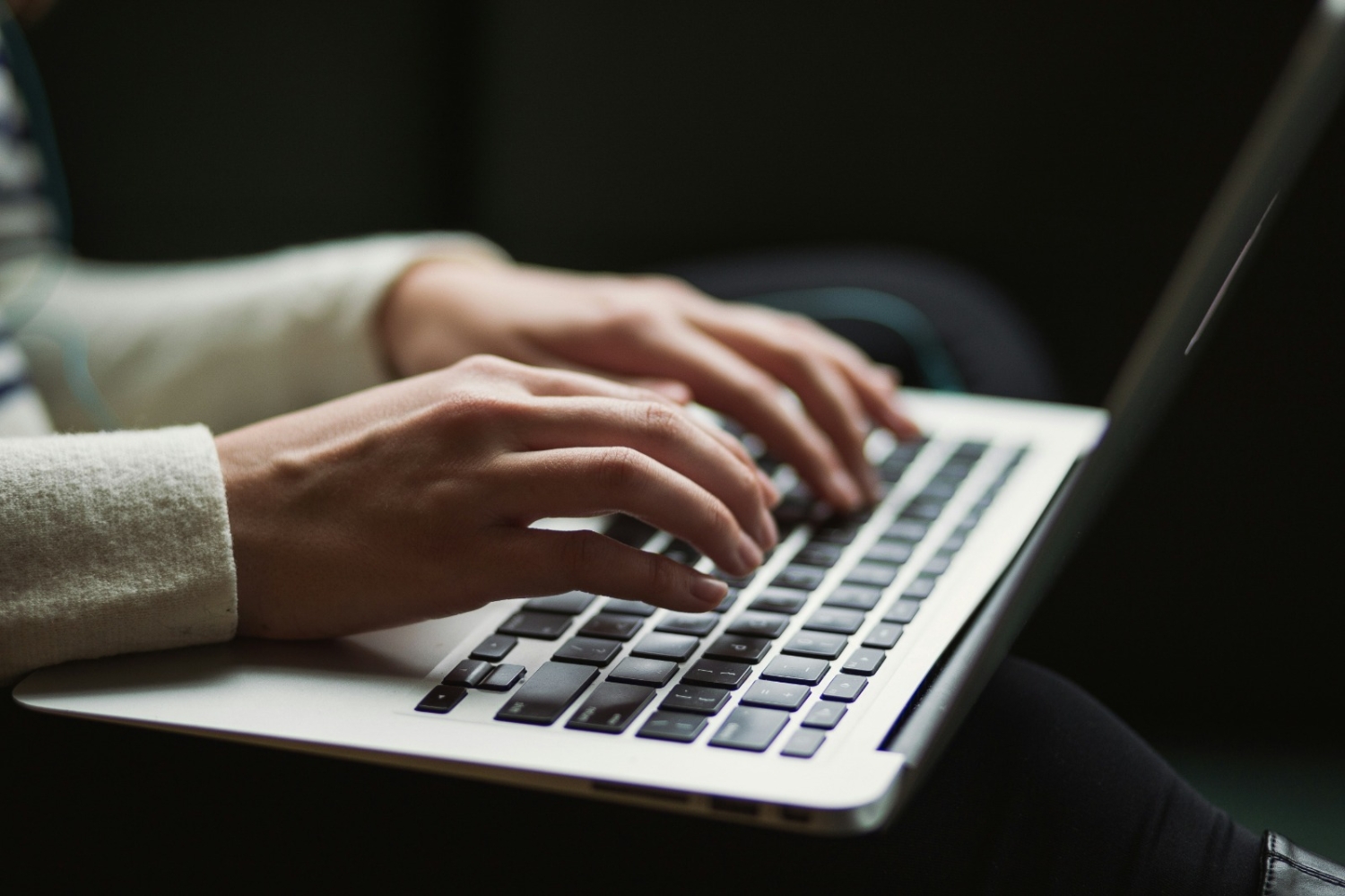 Tuvplānā klēpjdators un cilvēka rokas un tastatūras