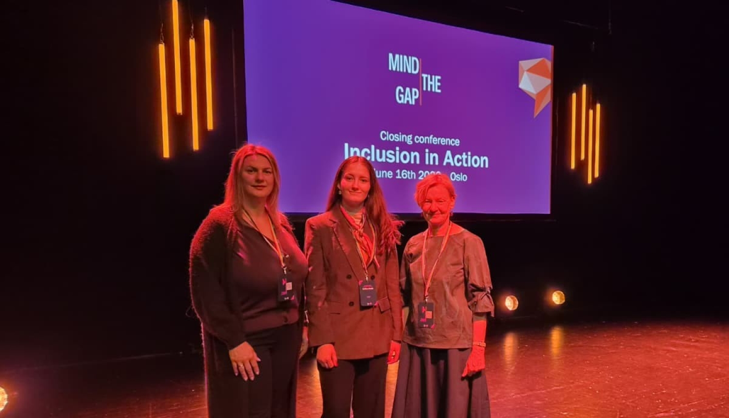 Latvijas delegācijas pārstāves starptautiskās konferences "Mind the Gap – Inclusion in Action" noslēguma pasākumā Oslo. Dalībnieces fotografētas uz skatuves, fonā redzams konferences nosaukums uz ekrāna.