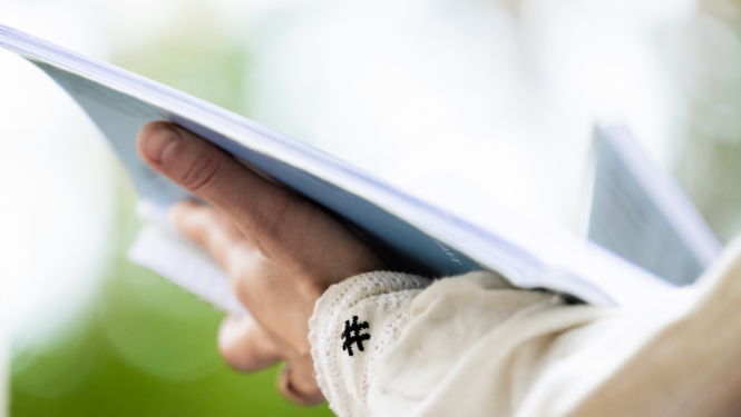 Tuvplānā roka kas tur dziesmu krājumu