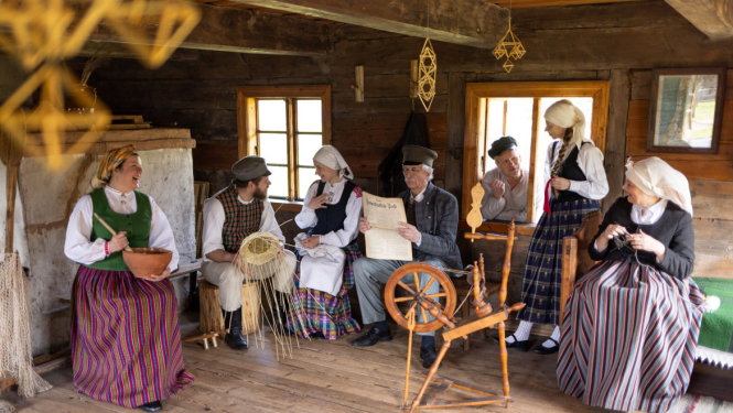 Cilvēki, tērpi tautastērpos, atrodas vienā no brīvdabas muzeja ēkām