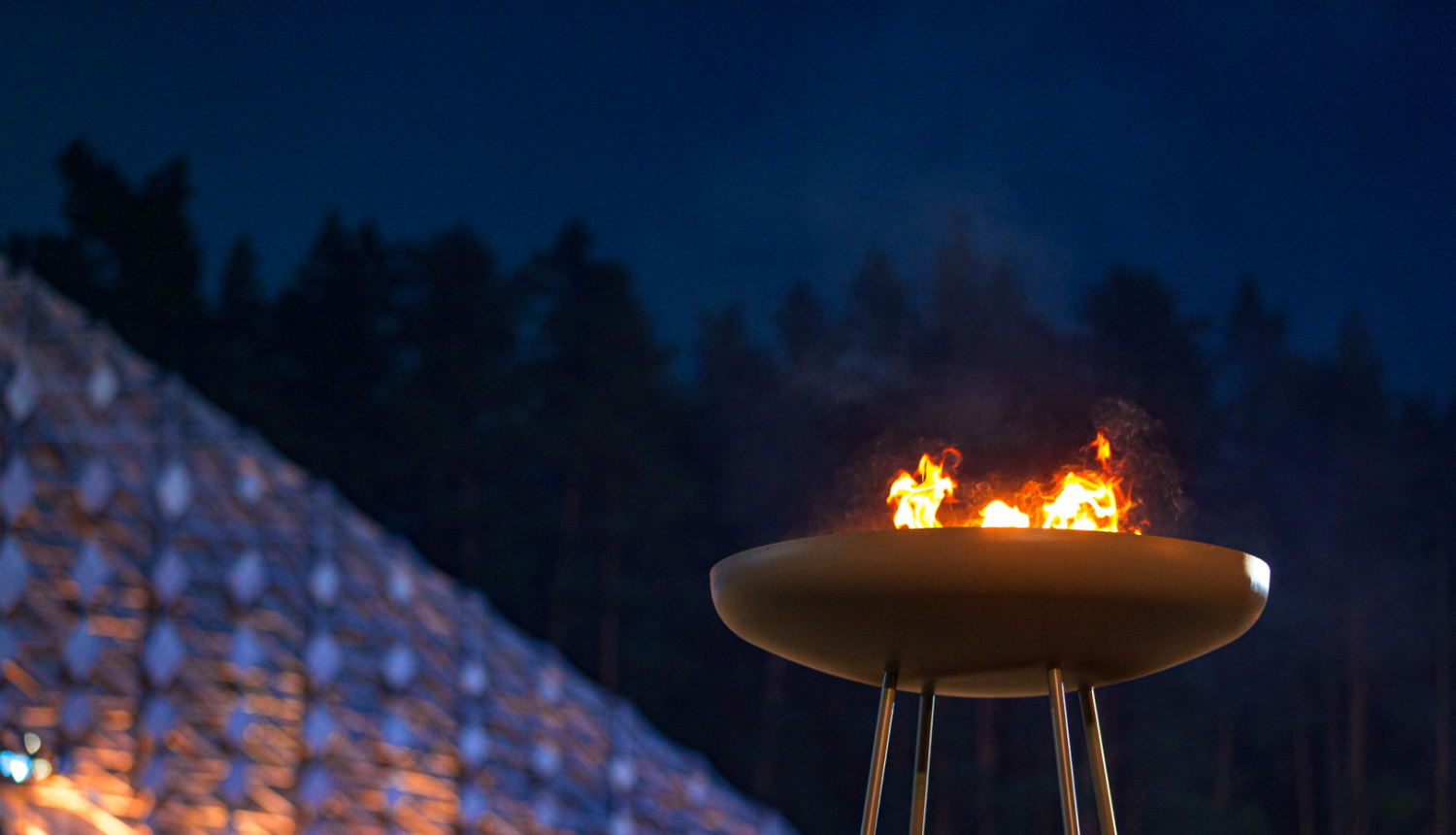 Lielā melnā metāla traukā redzamas uguns liesmas. Tas ir daļa no Dziesmu svētku scenogrāfijas Mežaparka Lielajā estrādē