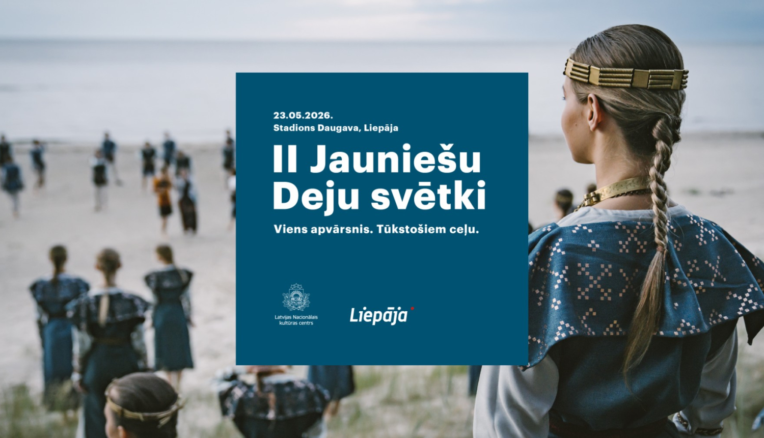 Deju kolektīva dalībnieki zilas krāsas tautas tērpos pie jūras